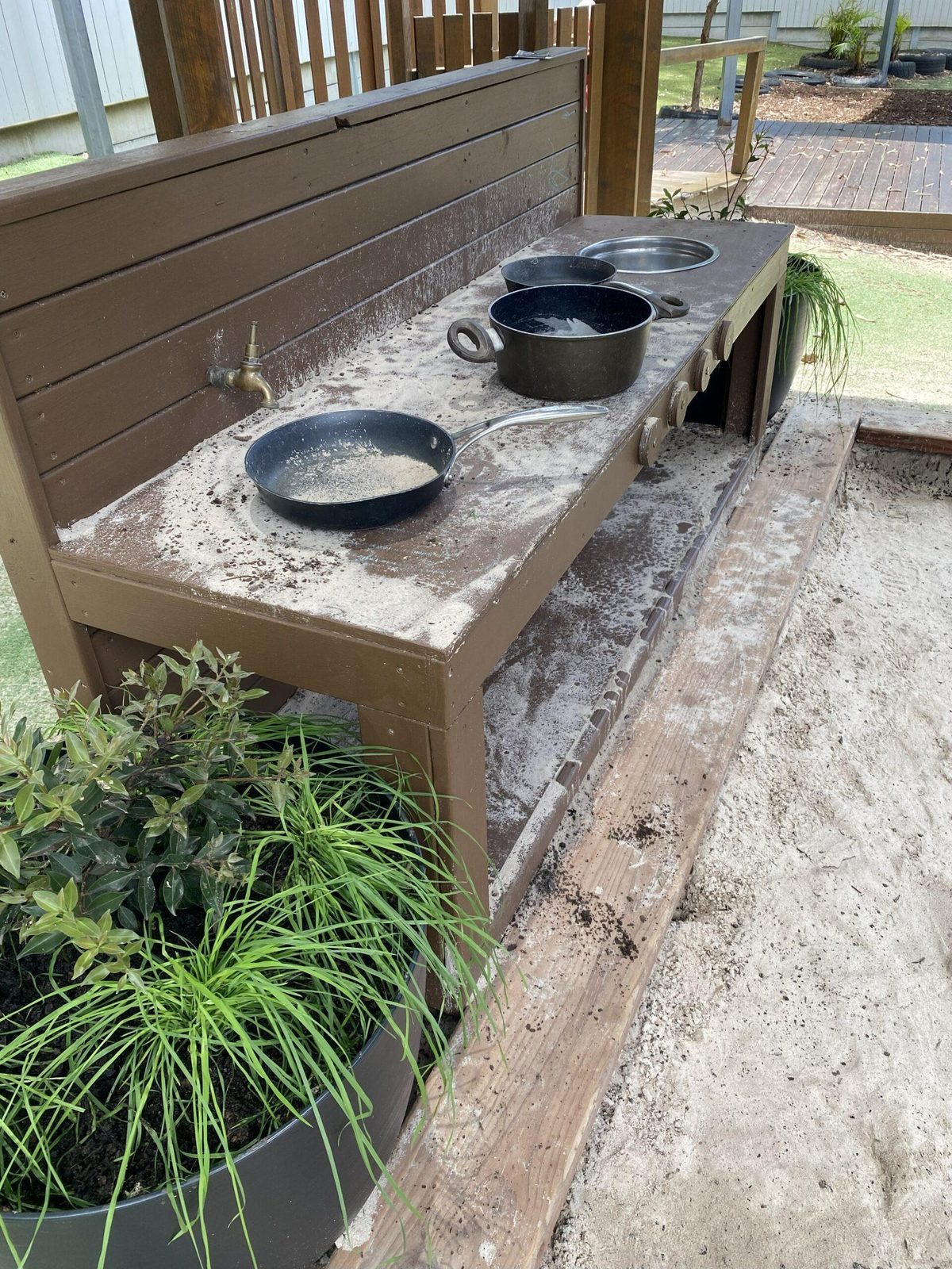 Outdoor mud kitchen with pots, pans and native grasses