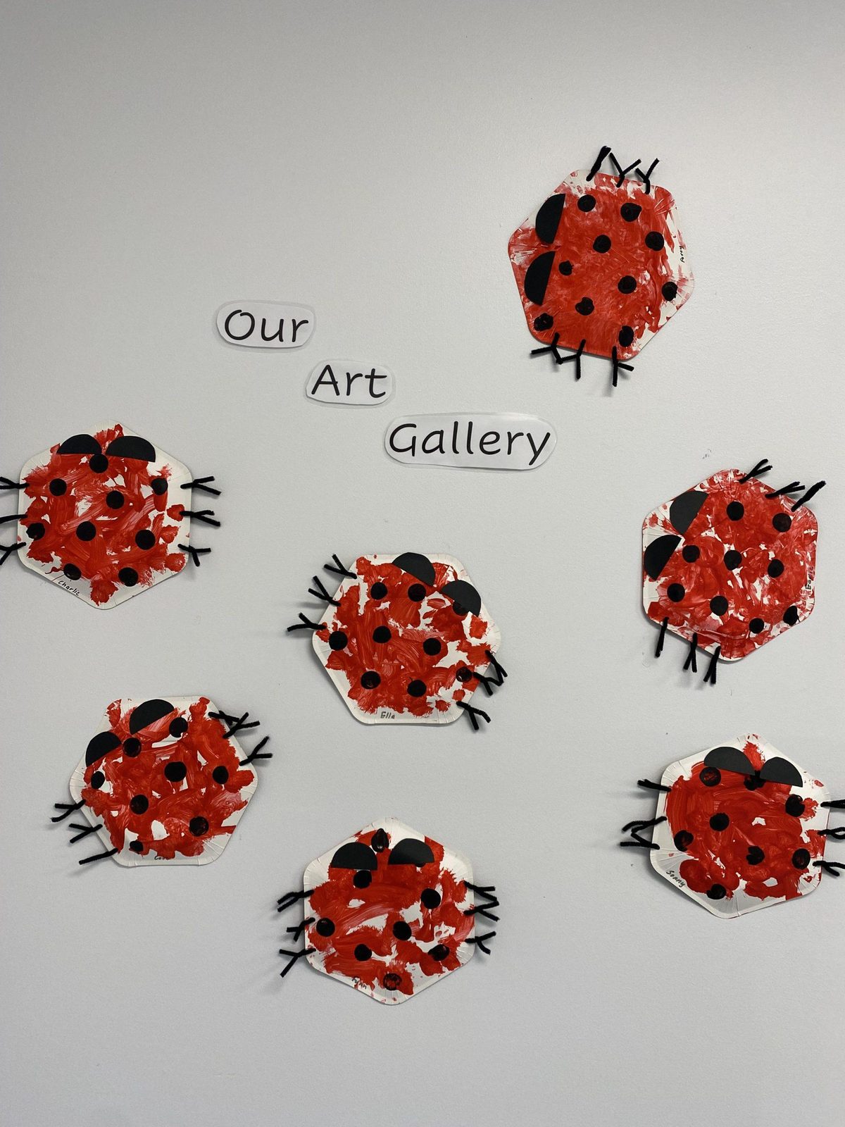Children's ladybird artwork displayed on the wall